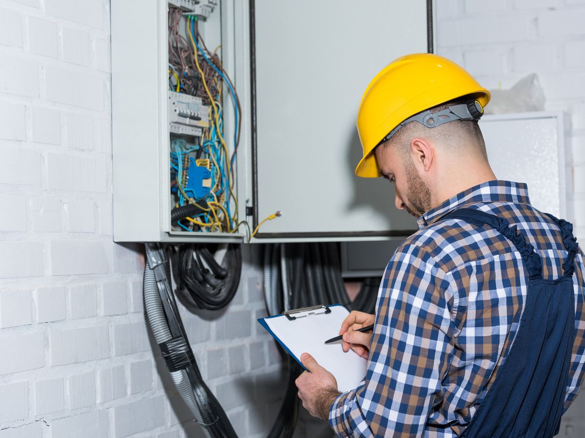 Electrician recording an inspection at a switchboard